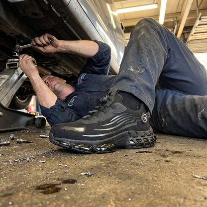 Mechanic working on a car with a focus on strovak flex black safety shoe